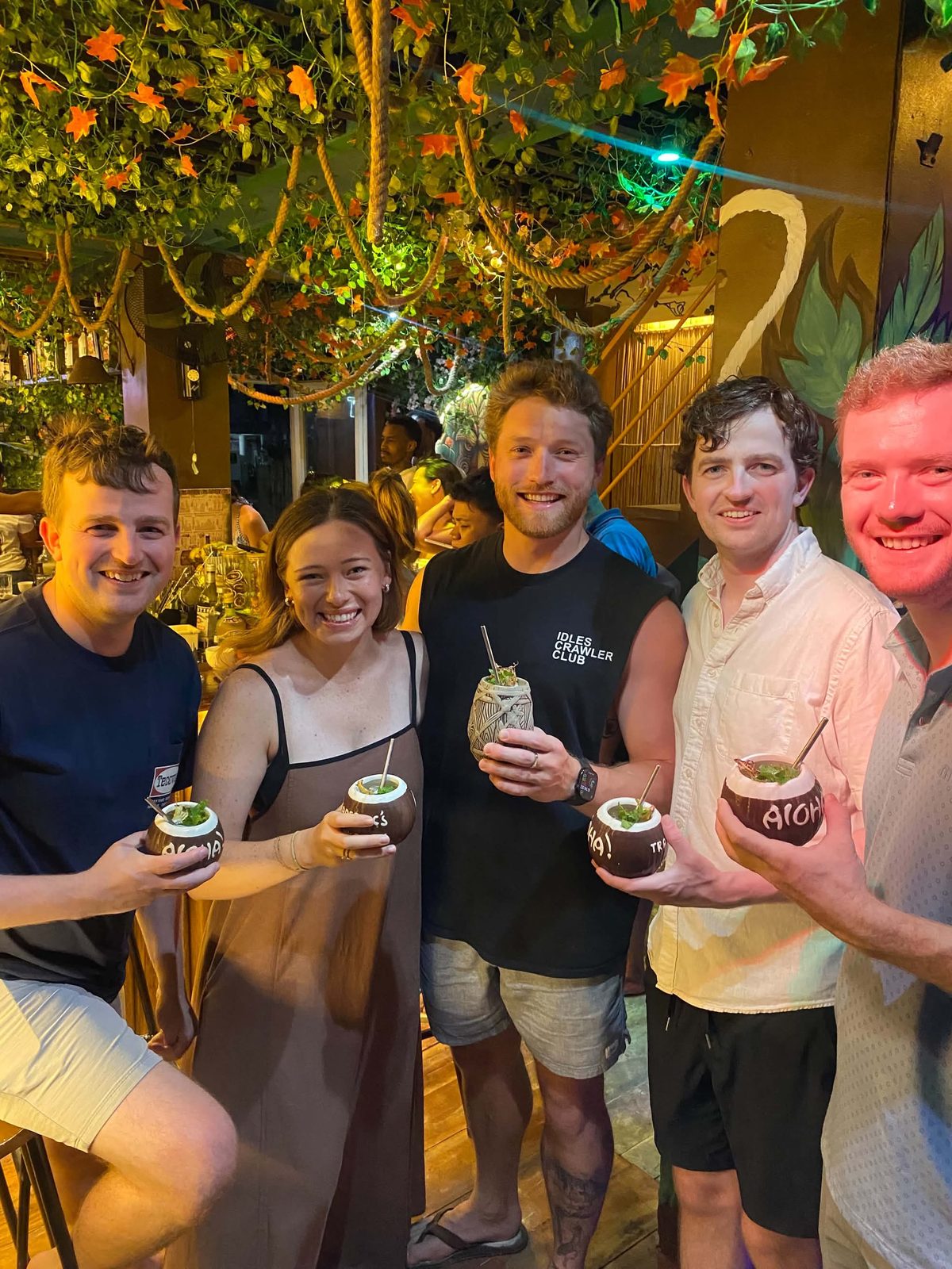 Guests raising carved tiki mugs together at Mai Tai Beach Bar Boracay